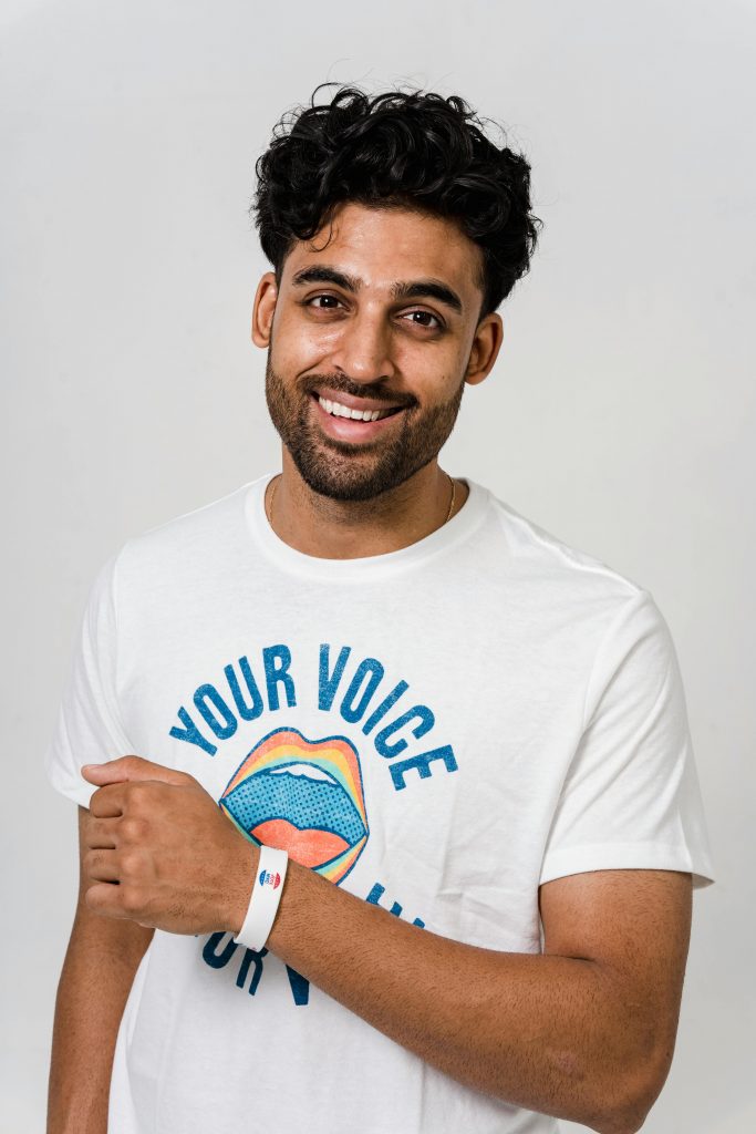 Smiling man with curly hair in a white t-shirt showing empowerment support.
